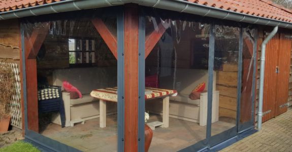 Grijze verandazeilen geplaatst bij blokhut